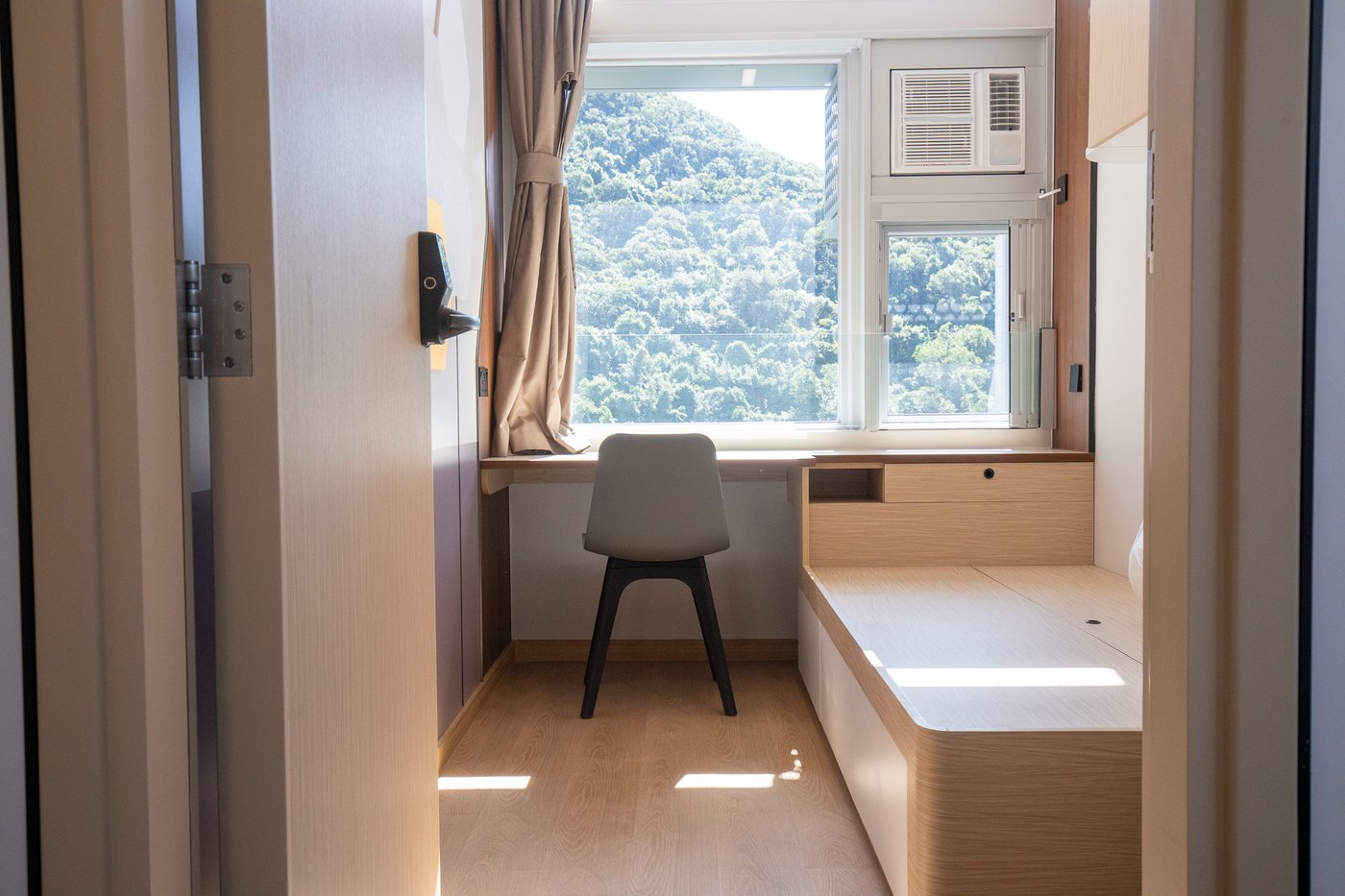 A single room with a desk under the window and a platform bed
